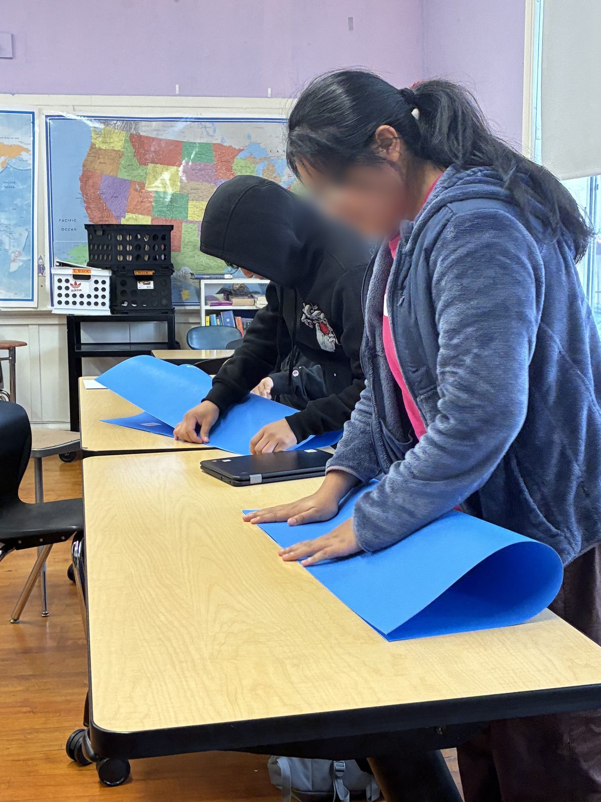 A Zymbolic educator working one-on-one with a student at a classroom desk